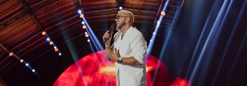 Show do cantor Belo no Via Music Hall em São João de Meriti, RJ, no dia 20 de abril de 2026, com público animado e decoração vibrante.